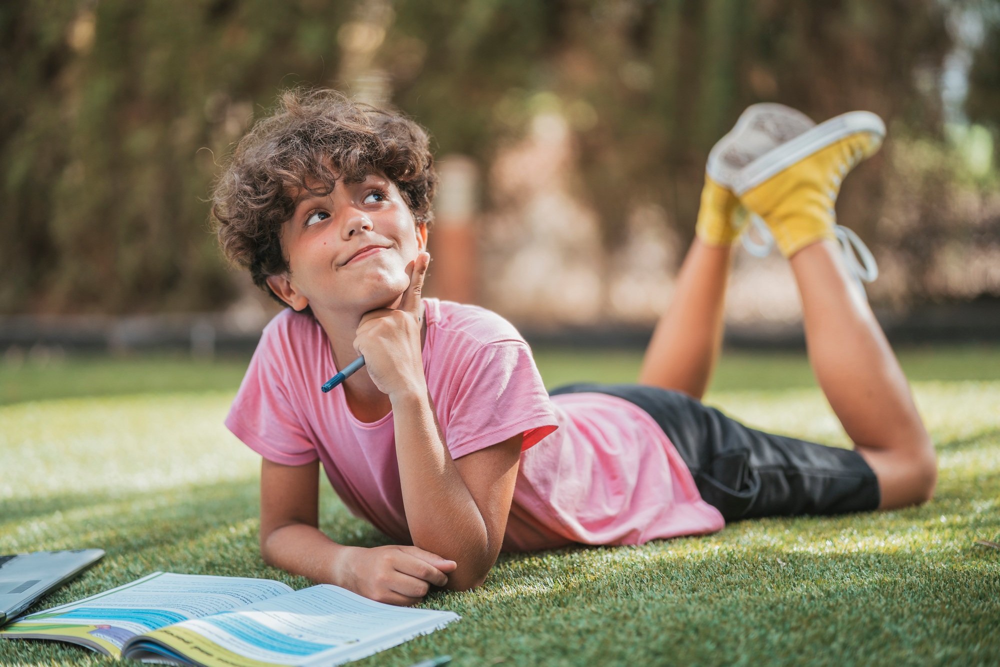 Boy lying in garden doing homework