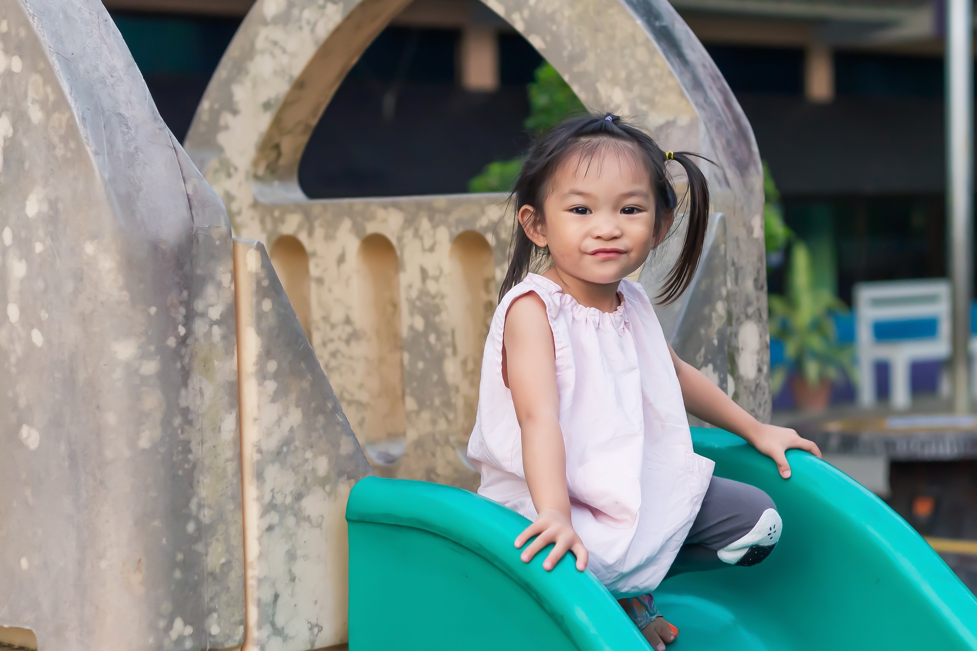 Happy Asian child girl playing with the slider bar toy at the playground.