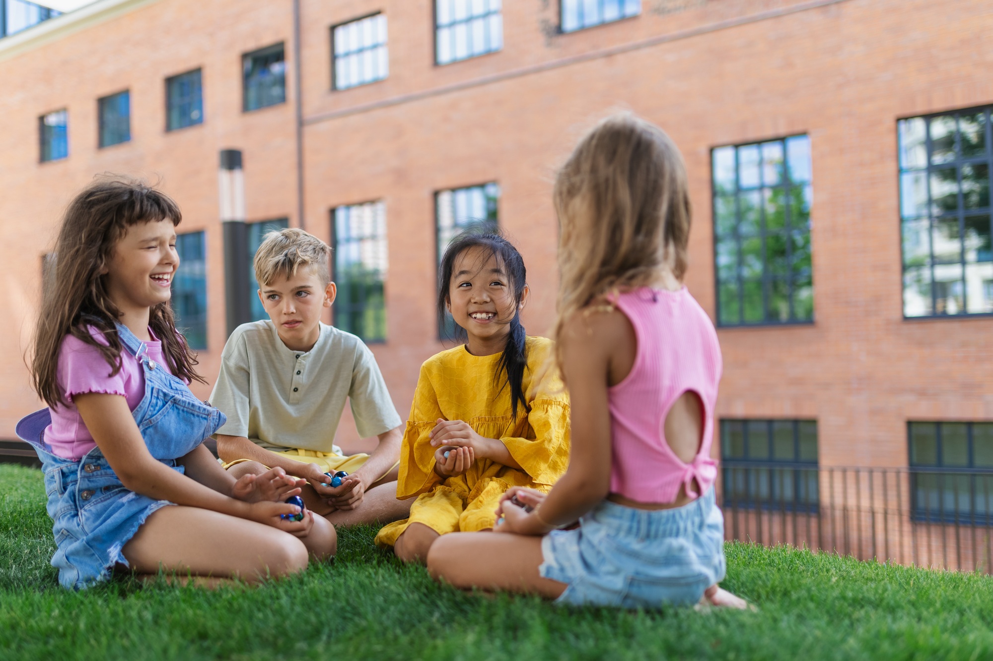 Happy kids playing and talking together in city park, during summer day.