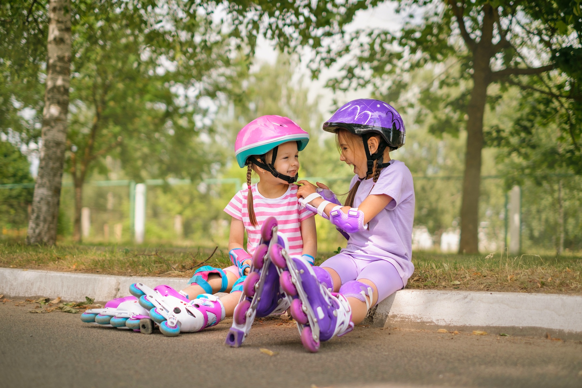 Kid helps sister fasten protective helmet for roller skating together in suburbs