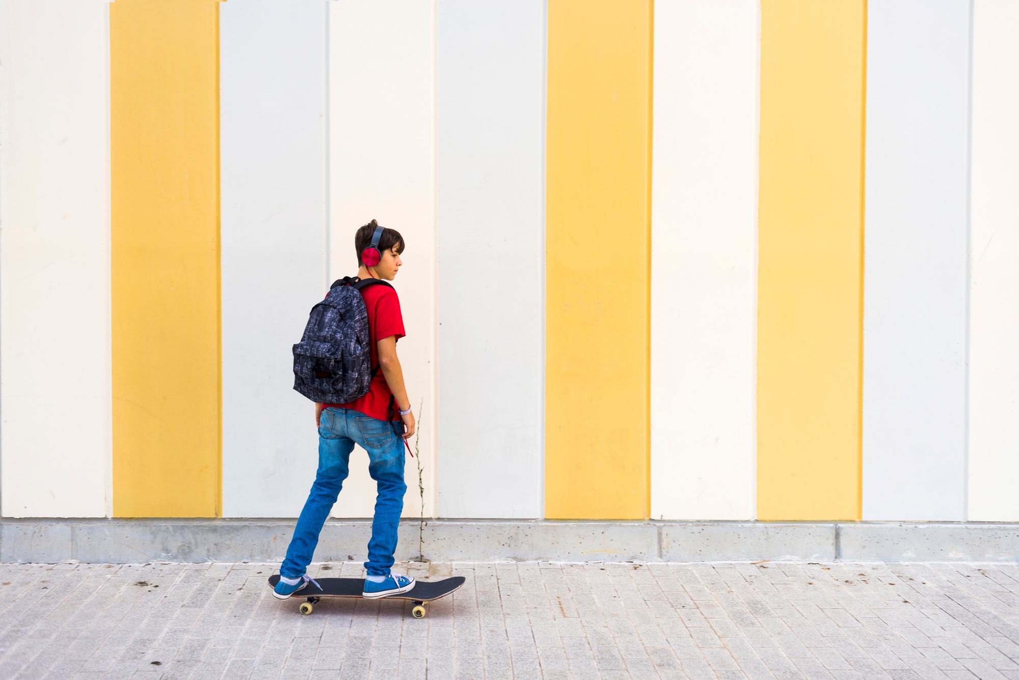 Kid in headphones skating on sidewalk
