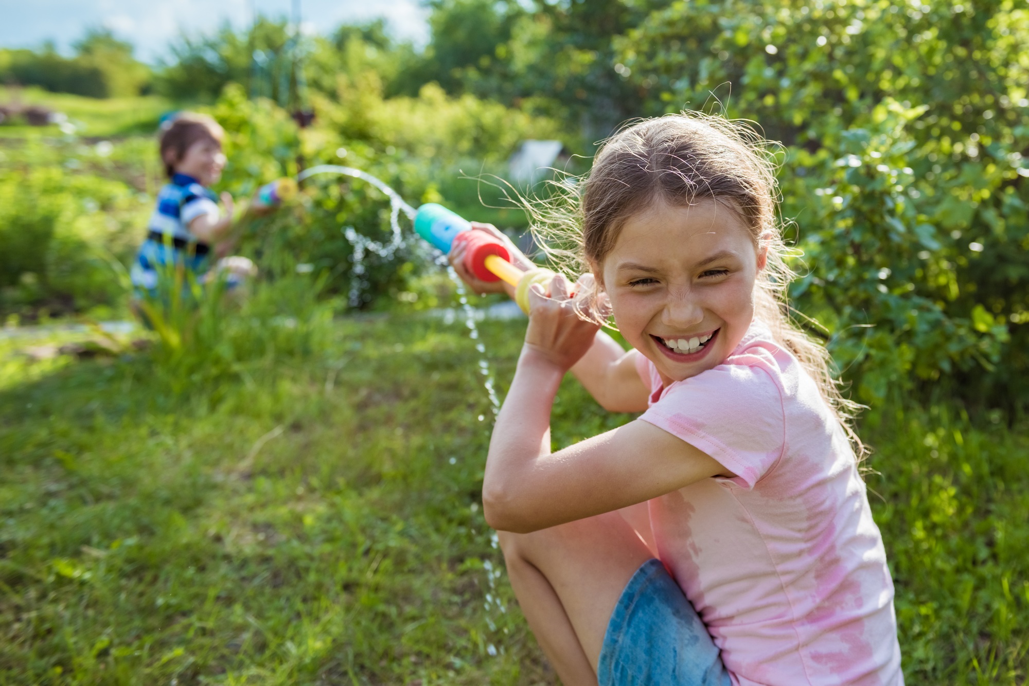Two little kids playing with water guns on hot summer day. Cute children having fun with water
